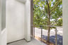 outdoor covered deck with glass enclosure and view of street with trees