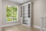 library space with large window, wood floors, and light gray built-in book shelves