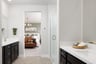 bathroom with black cabinets, white counters, dual separate vanities, shower, and tan tile floor
