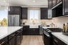 kitchen with wood floors, black cabinets, white counters, island, and window above sink