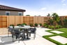 backyard with grass, and concrete patio with round dining table and four gray chairs
