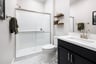 bathroom with black cabinets, white counters, two wood shelves, and walk-in shower