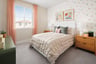 bedroom with butterfly wallpaper behind bed, gray carpet, and window with sheer peach panels