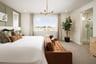 bedroom with gray carpet, green wall, brown sofa at end of bed, and gold hanging light fixture