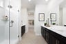 bathroom with tan hexagon tile floors, black cabinets, white counters, and walk-in shower