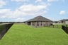 large backyard with wrought iron fence, grass, and covered patio