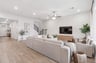 great room with brown flooring, windows and a ceiling fan