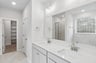 primary bath with dual sinks and white flooring