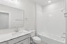 secondary bathroom with white flooring, a sink and a soaking tub