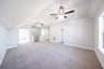 open loft with carpet and ceiling fan