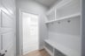 mudroom with wood floors and white shelves with bench