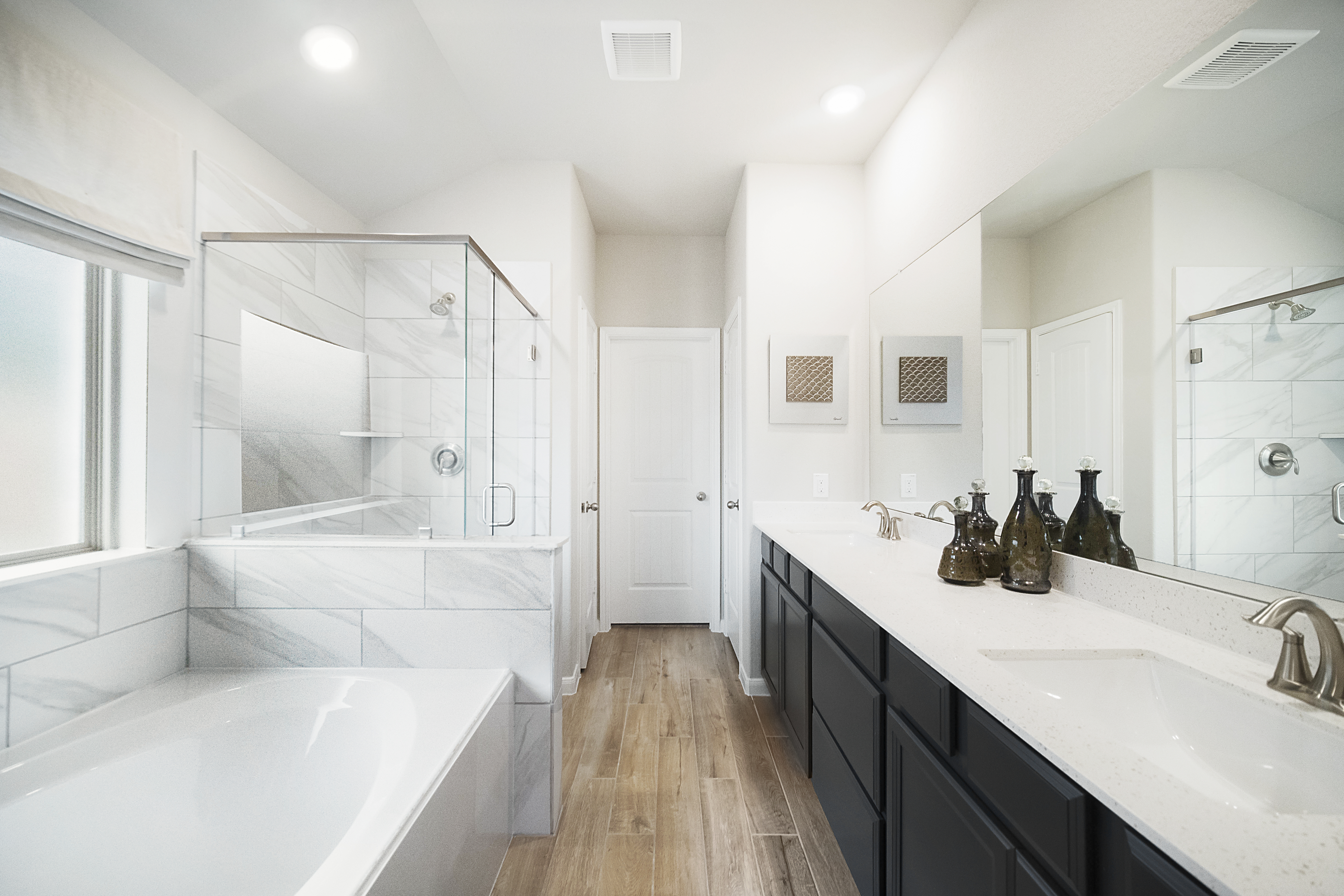 primary bathroom with double sinks and white tub